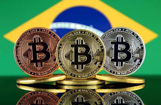 moedas de bitcoin na frente de bandeira do Brasil